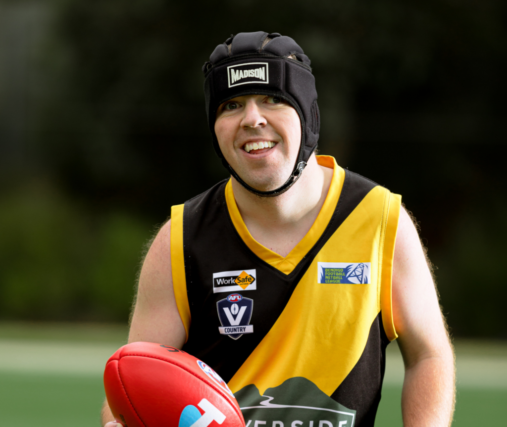 Hayden, footy player and sports fanatic​ holding a footy.