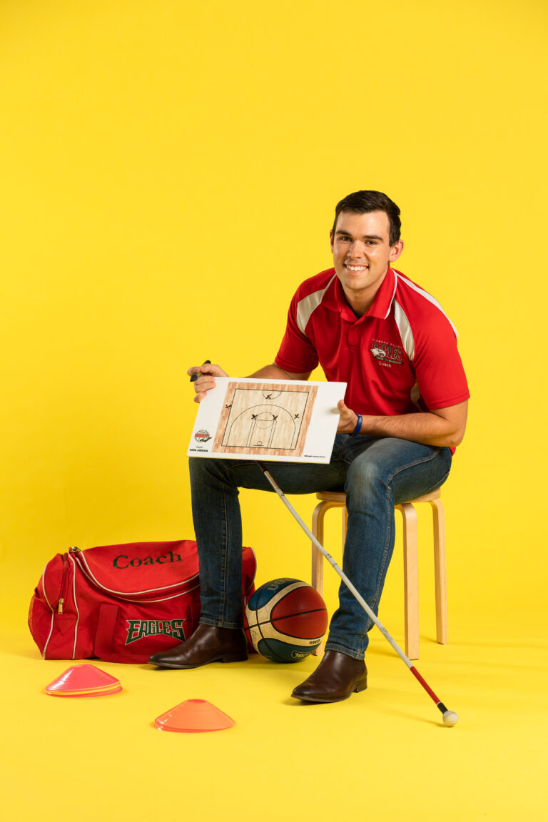 A basketball coach sitting on a chair and making plays.