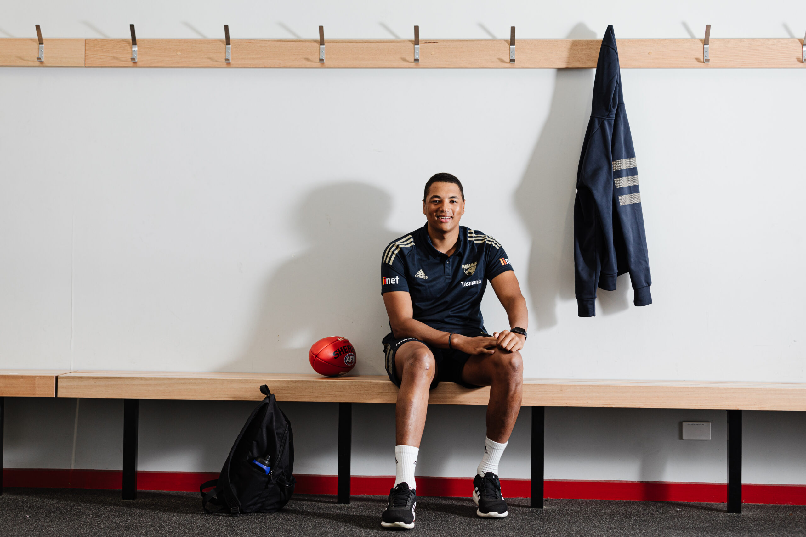 Athlete sitting on a bench with a ball next to him.