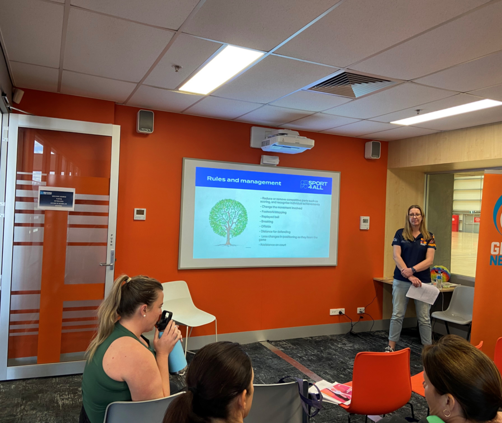 Sport4All Inclusion Coach Jenny presenting to an audience seated in chairs, attentively listening.