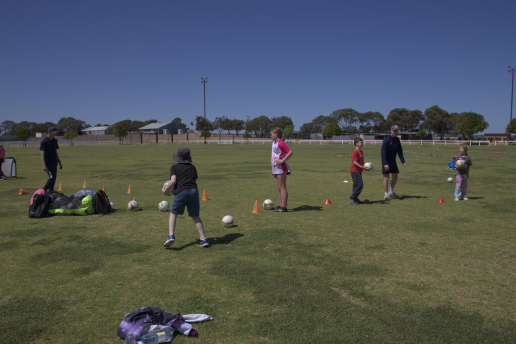 A group of kids playing together. Cones, balls and other sports equipment is lying on the ground as part of training.