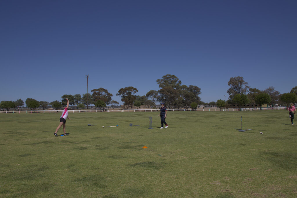 A young girl about to bowl a cricket ball.