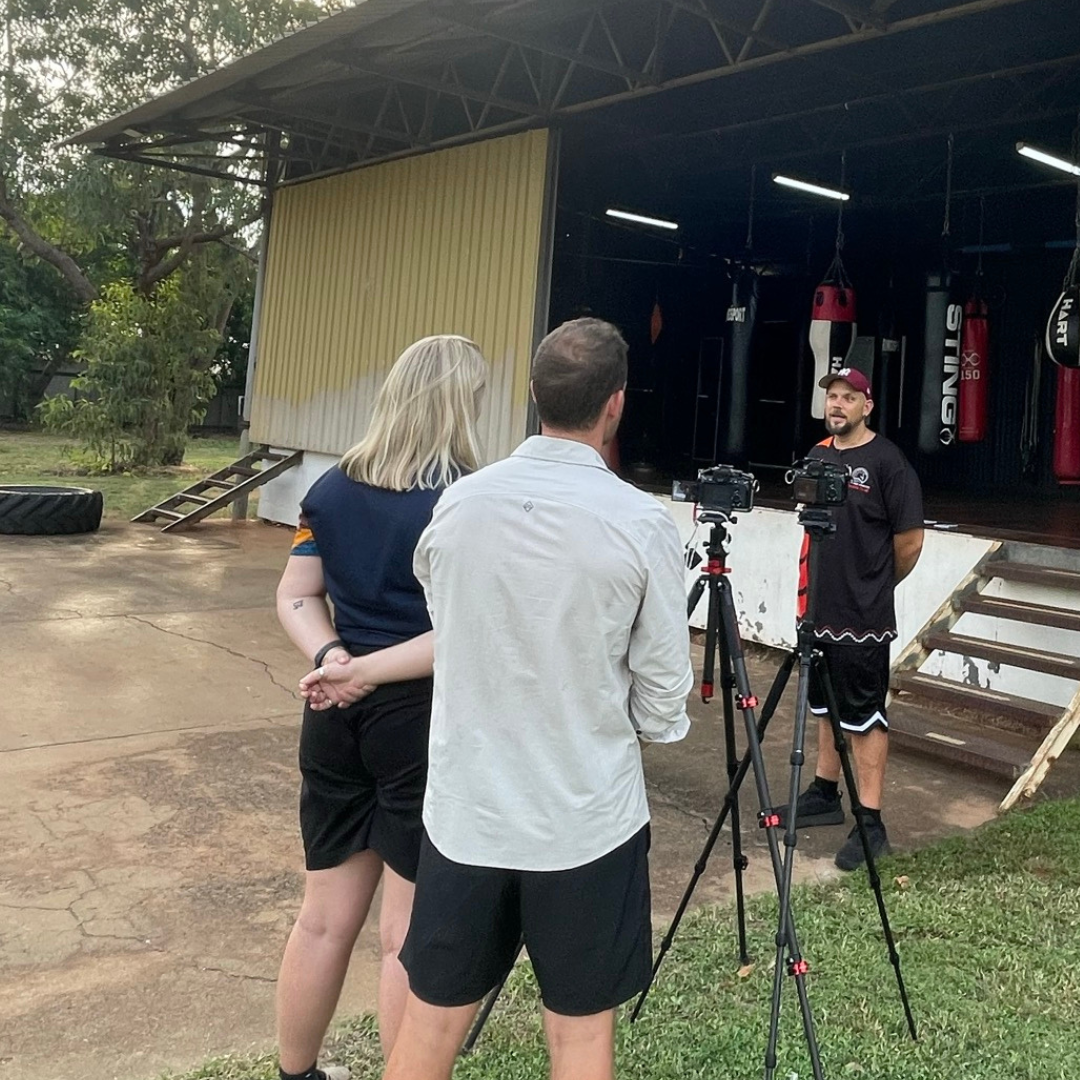 A behind the sceens like image of Sport4All team and the camera enquipment when interviewing a boxing coach in front of the training center.
