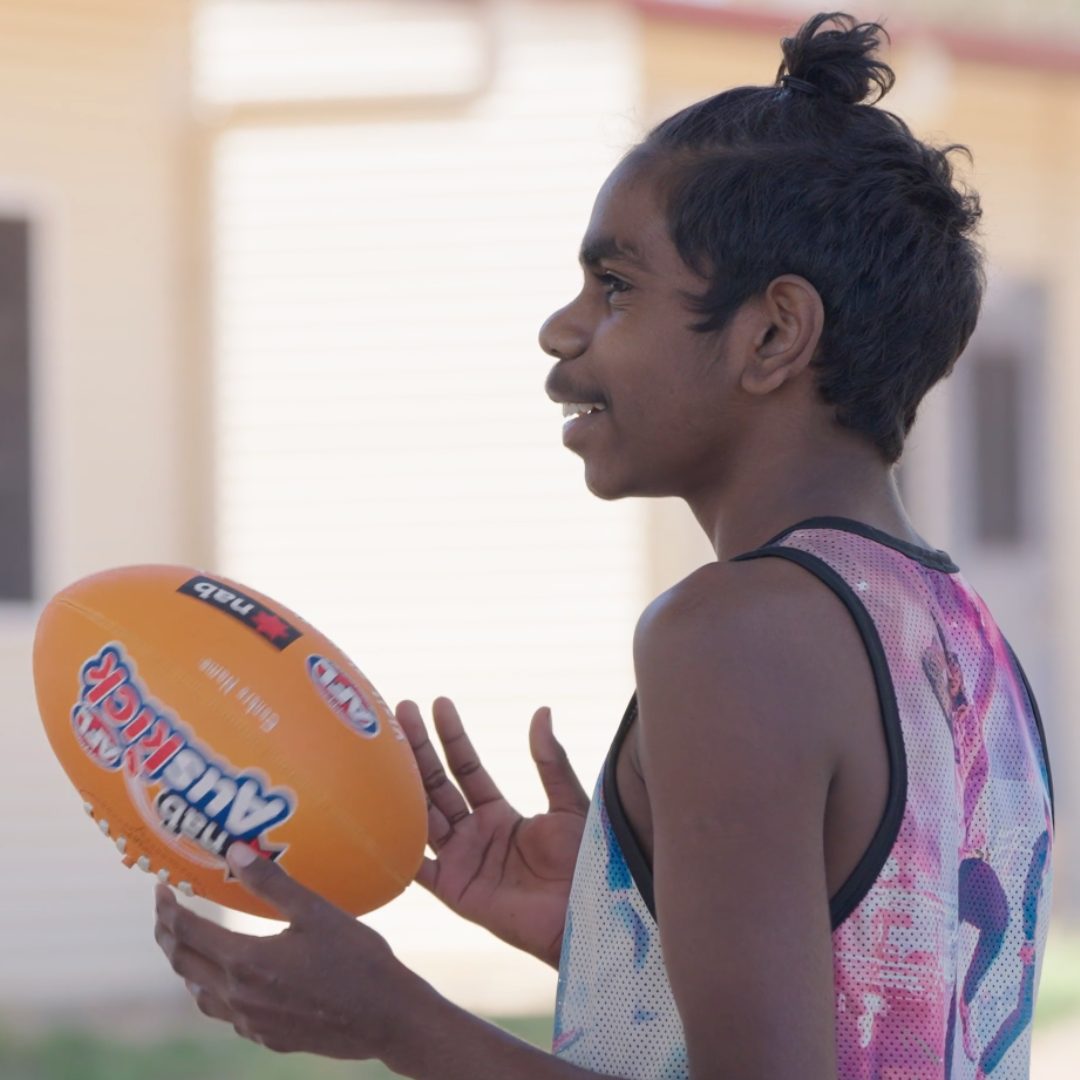 A person holding a footy in his hand.