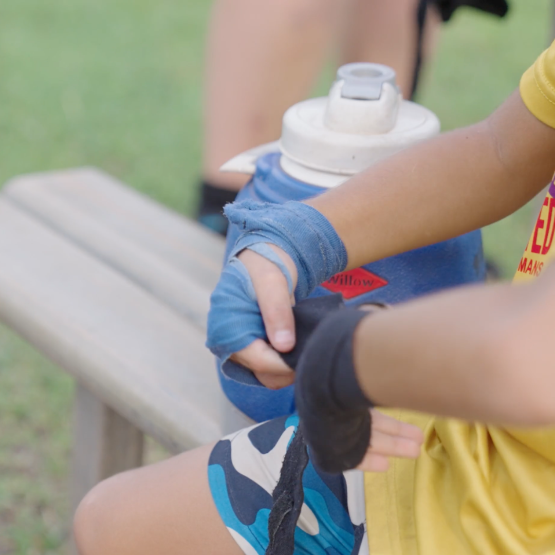 A close up of someone putting on boxing gloves.