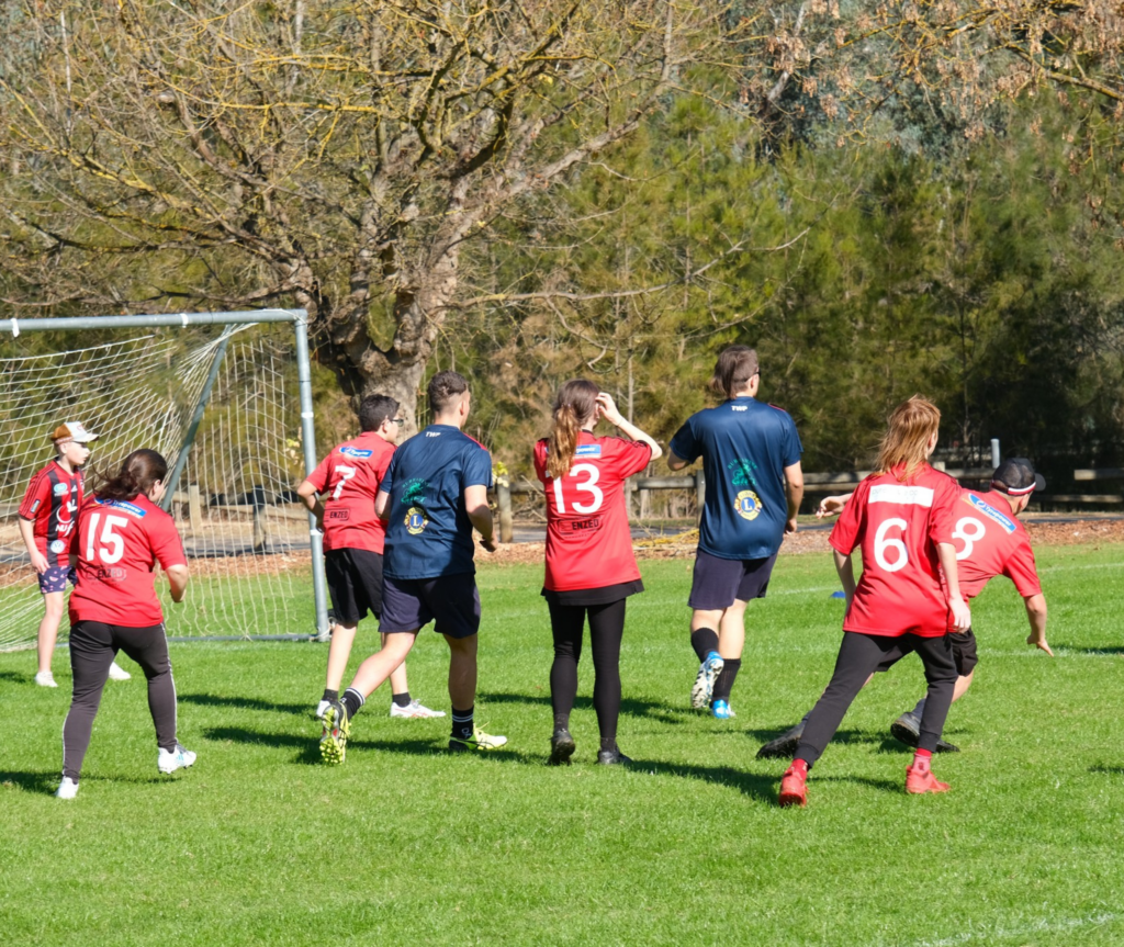 A group of people playing soccer wearing red and blue shirts.
