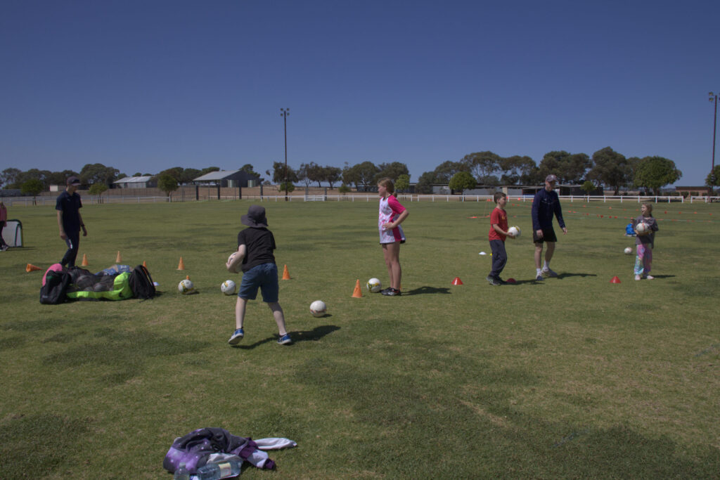 A group of kids playing together. Cones, balls and other sports equipment is lying on the ground as part of training.