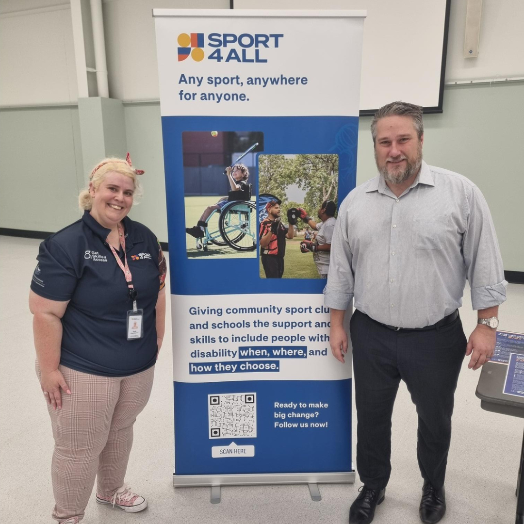 Sport4All Inclusion Coach, Emily with Cr Jim Moloney next to Sport4All banner inside a community hall.