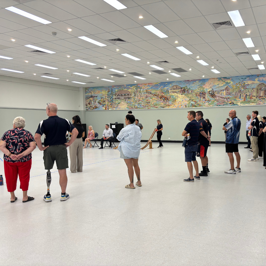 Participants stand in a circle during a practical inclusion activity in a hall.