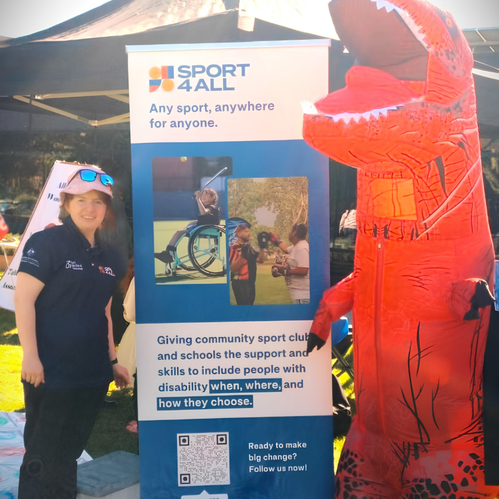 Sport4All Inclusion Coach Marnie Shannon, alongside a Sport4All banner at an outdoor event next to a red inflatable dinosaur.