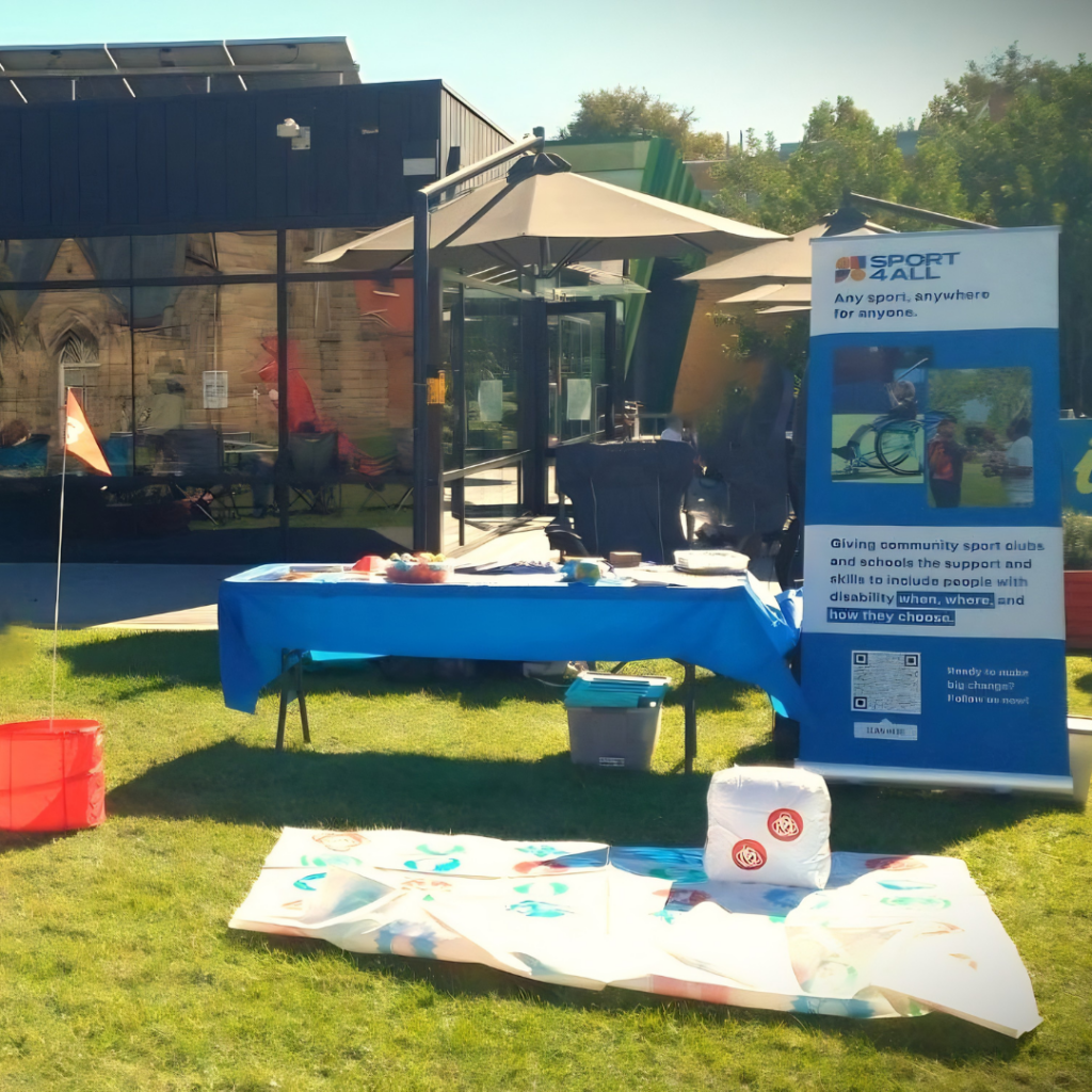Sport4All information stall set up outdoors with a banner, table and activity area on grass.