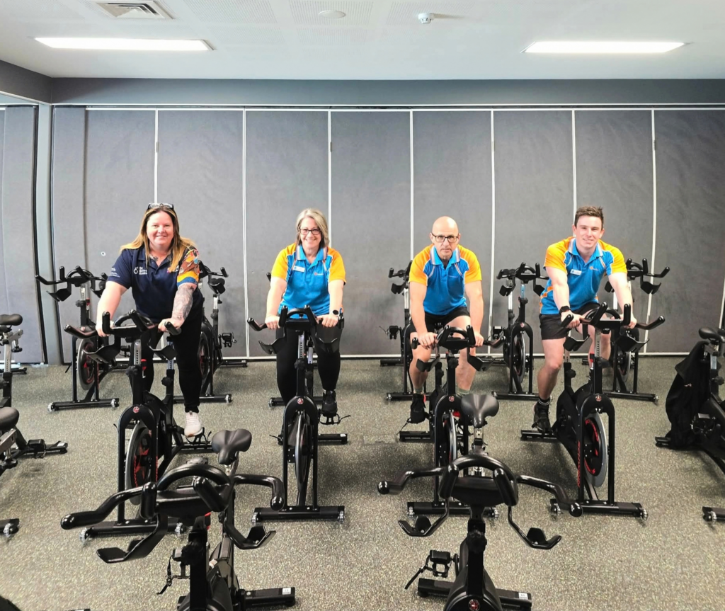 Sport4All Inclusion Coach, Jo with Splash team members on an exercise bike.