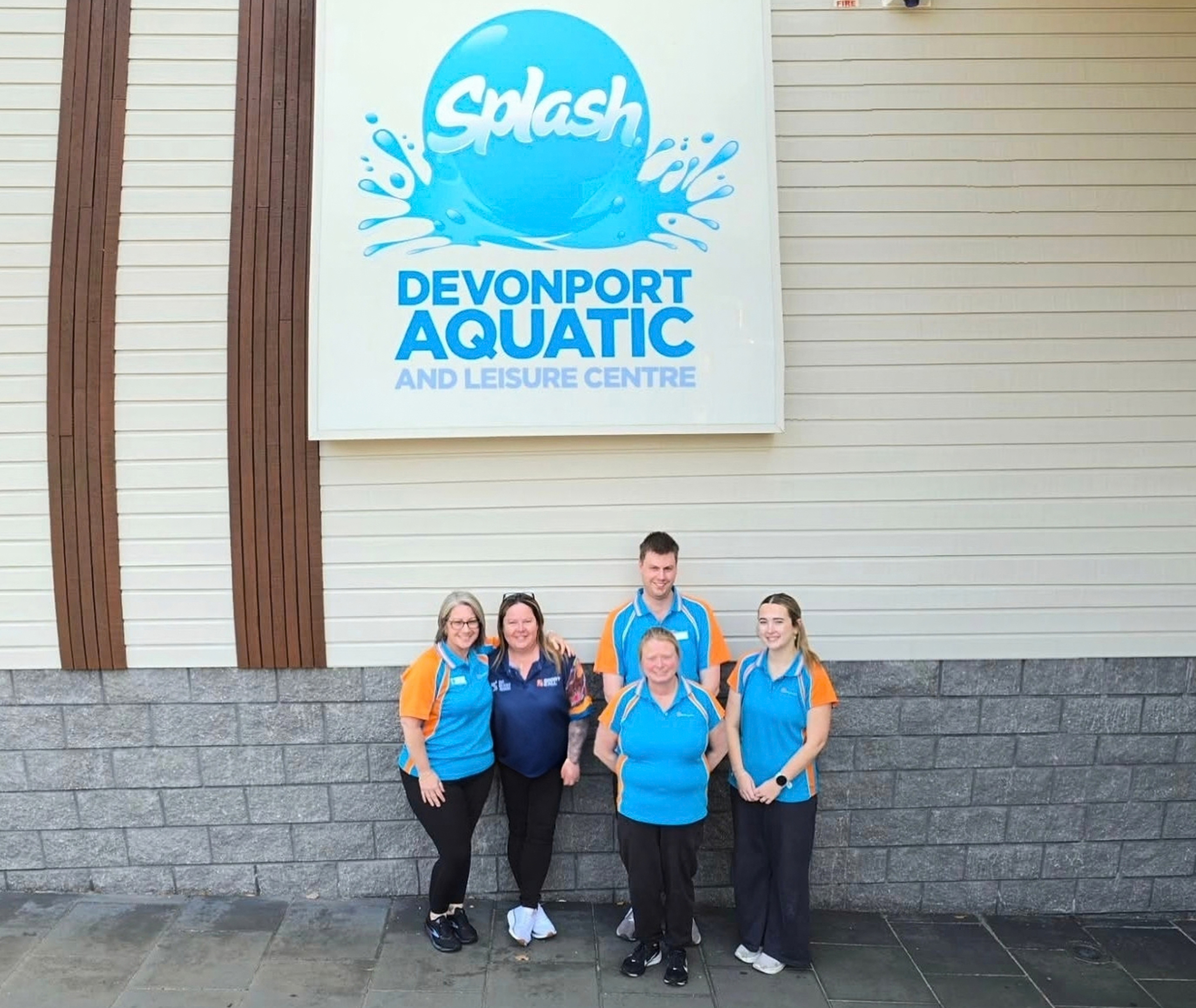Splash Devonport Aquatic and Leisure Centre staff members alongside Sport4All Inclusion Coach Jo stand beneath the centre’s sign outside the building.