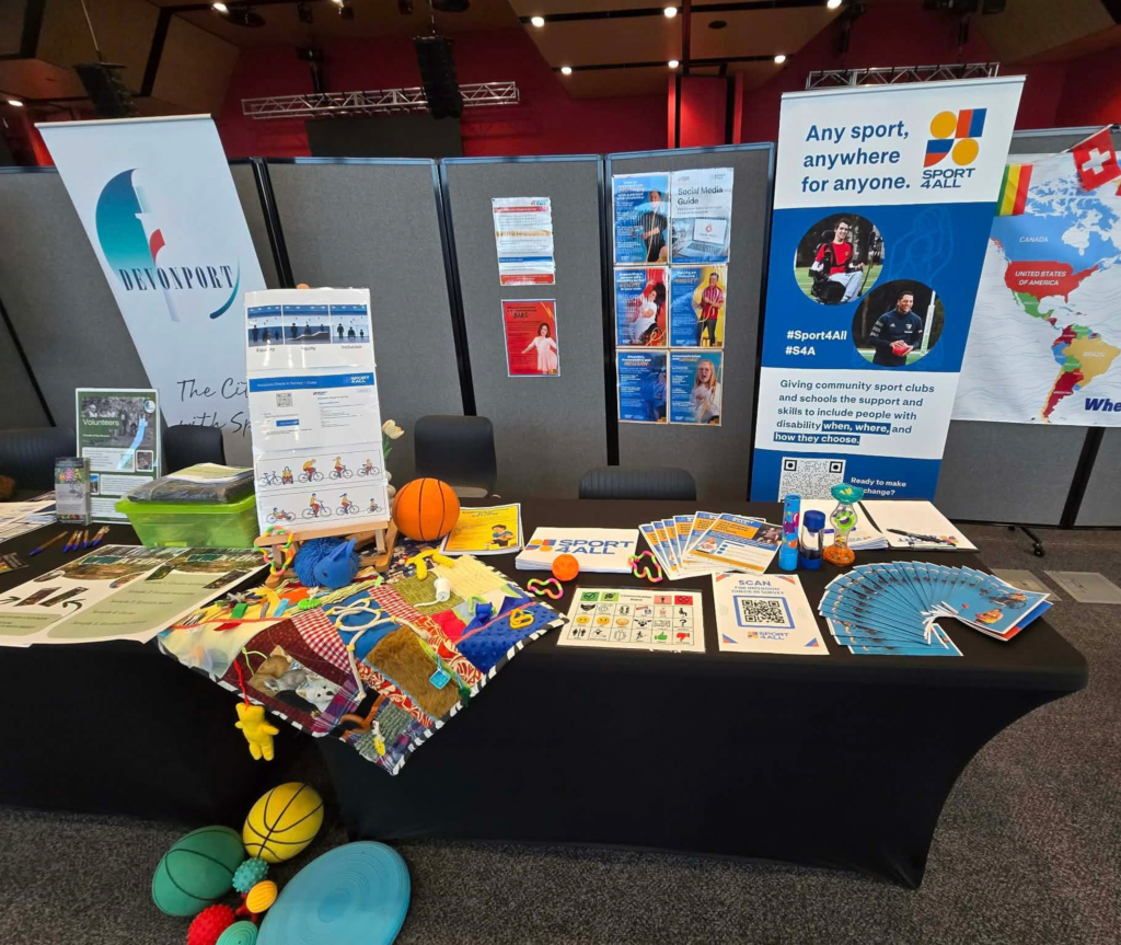 Sport4All information stall with inclusive sport resources and adaptive equipment at a community expo.